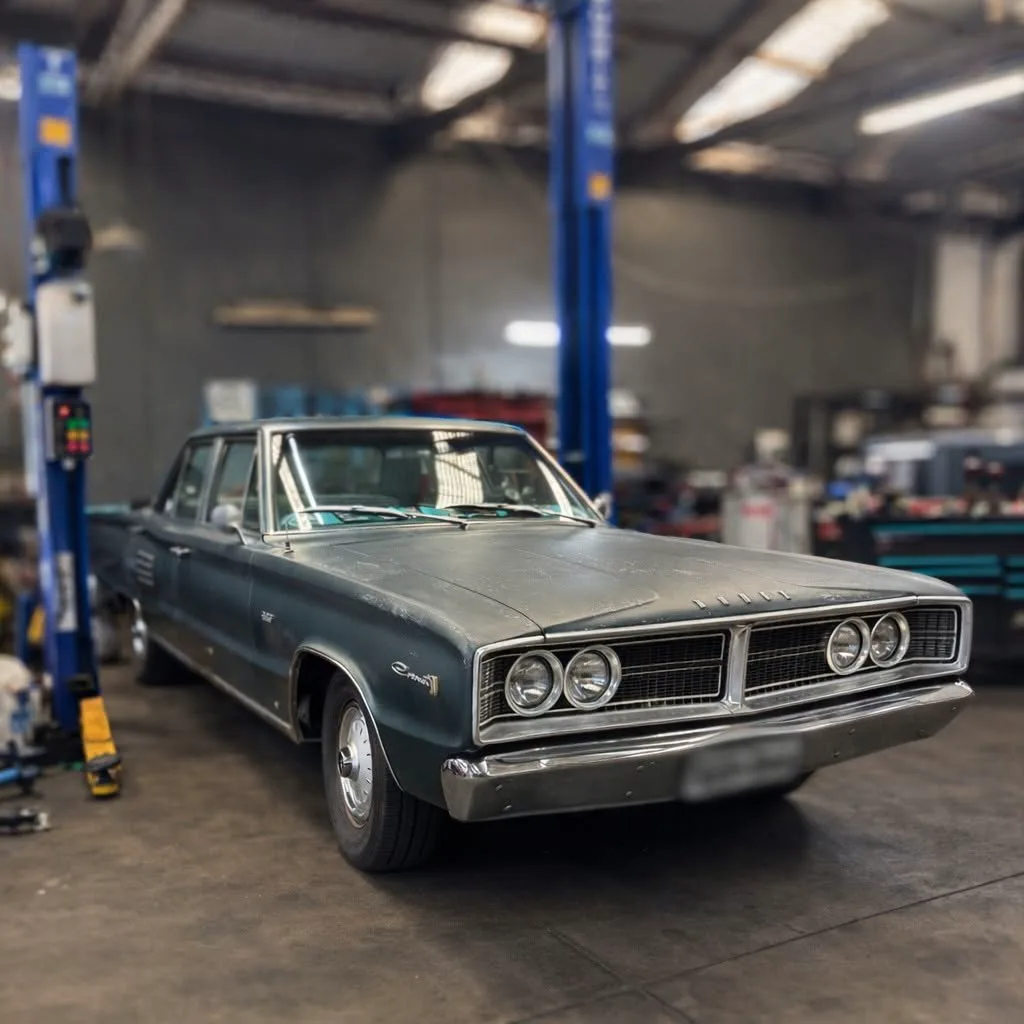 A classic Chrysler raised on the two post hoist inside the workshop