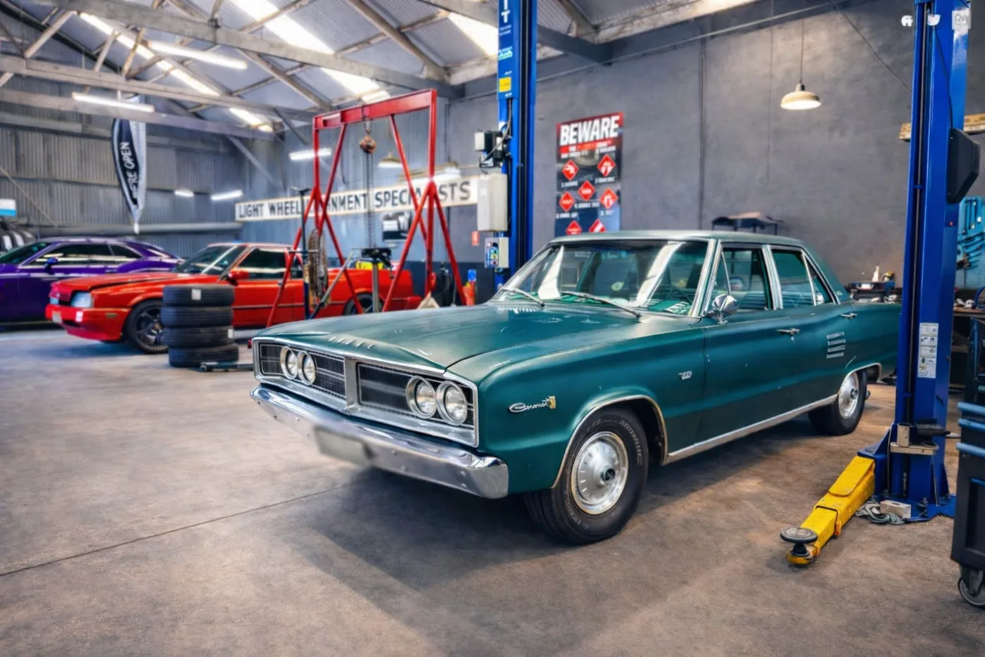 A classic sedan between the hoists inside the workshop