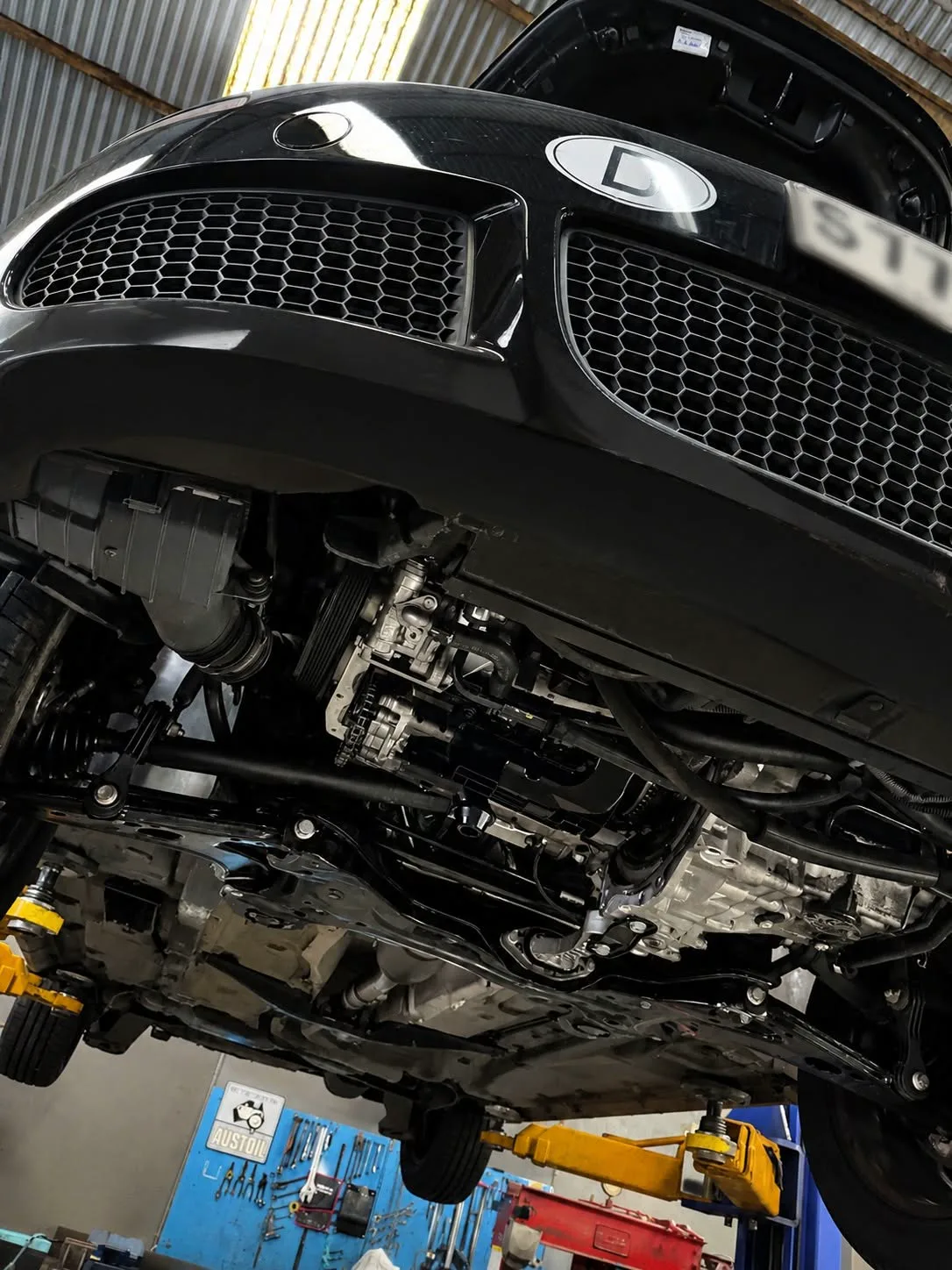 A technician inspecting front suspension components from underneath a raised vehicle