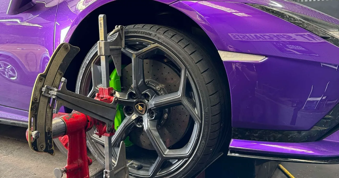 An alignment clamp fitted to the front wheel of a car on the rack